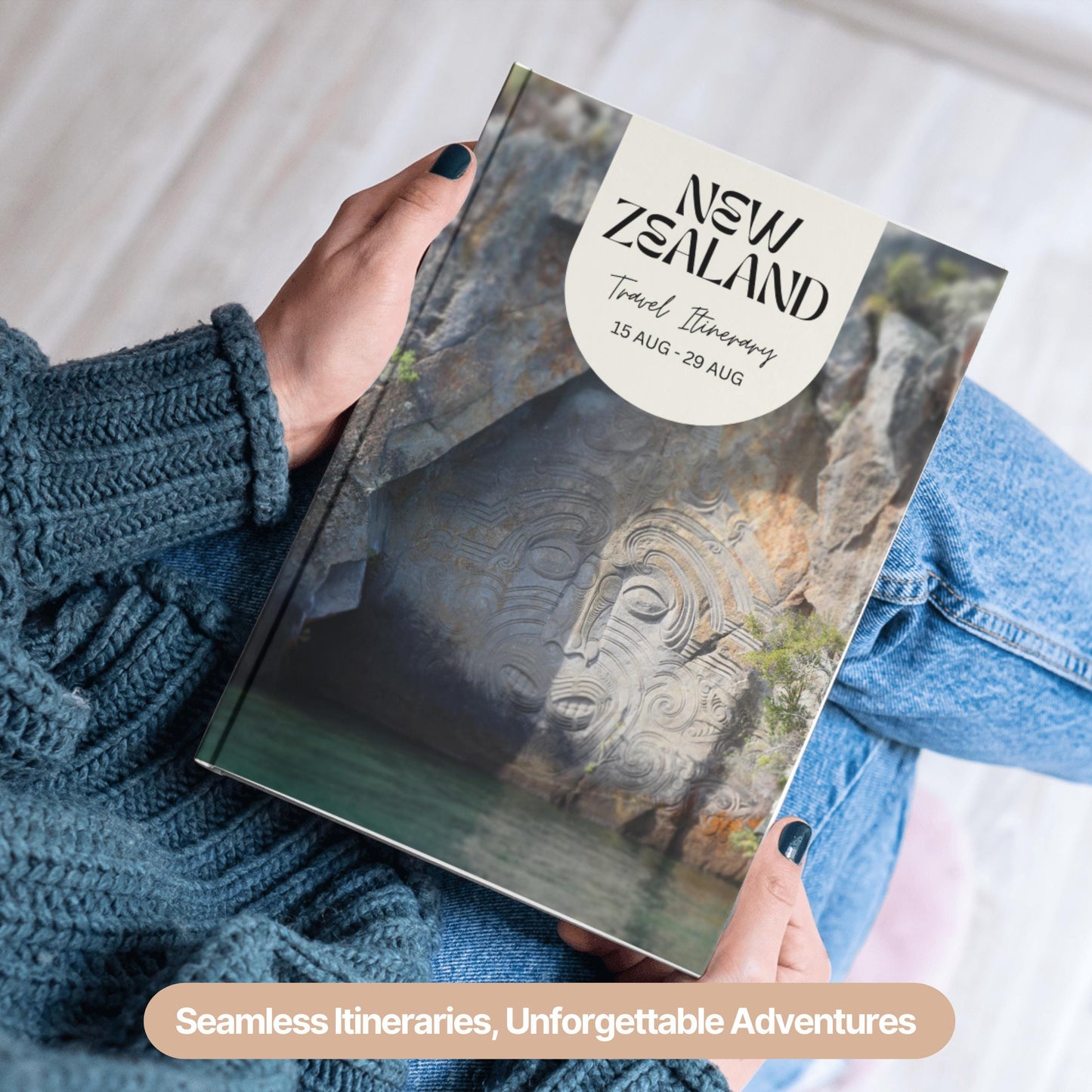 A person wearing a cozy blue sweater and jeans is holding a hardcover travel itinerary book.
