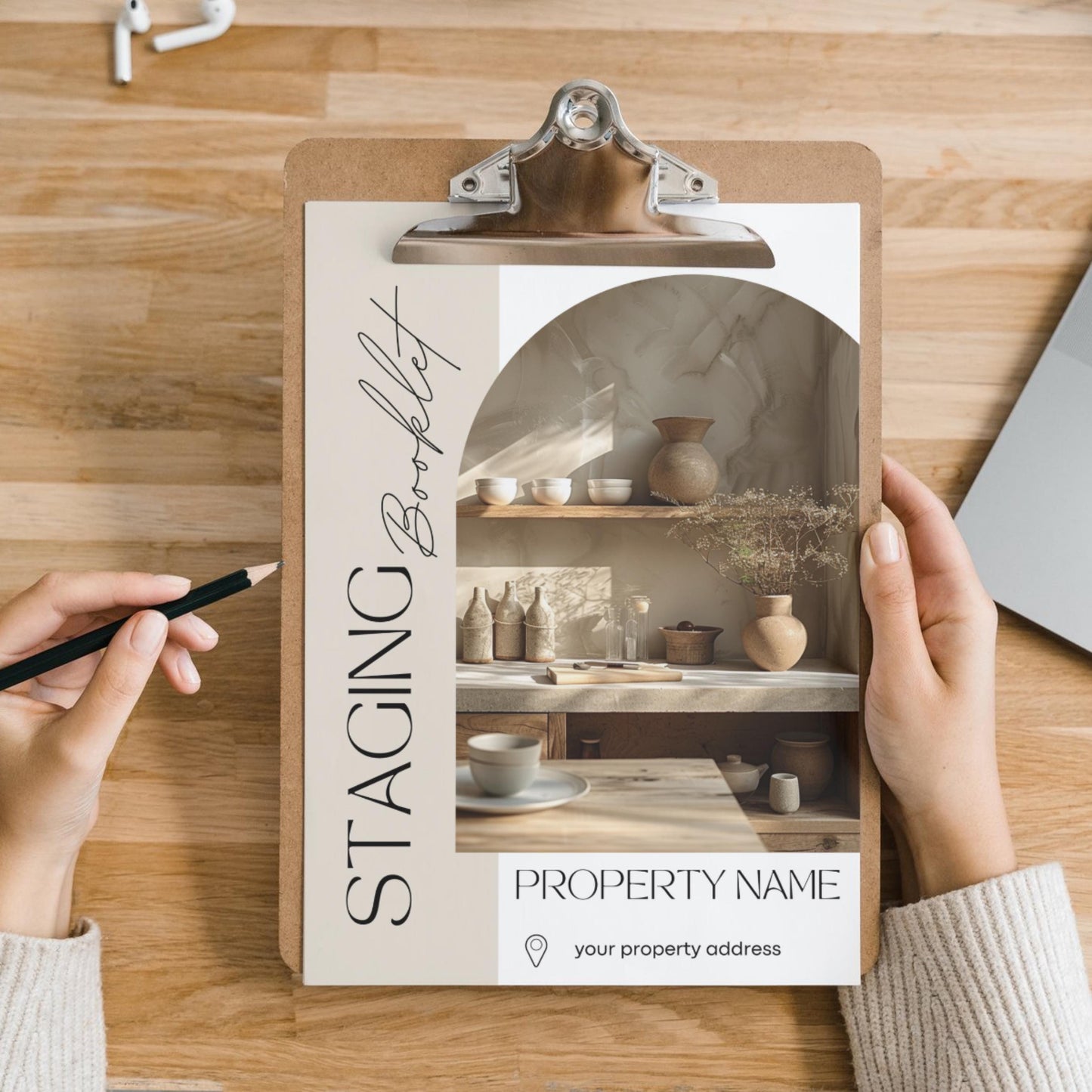 A person holds a clipboard with a “Staging Booklet” displayed on top, designed for a property listing. The cover features a modern, minimalist layout with soft beige tones. 