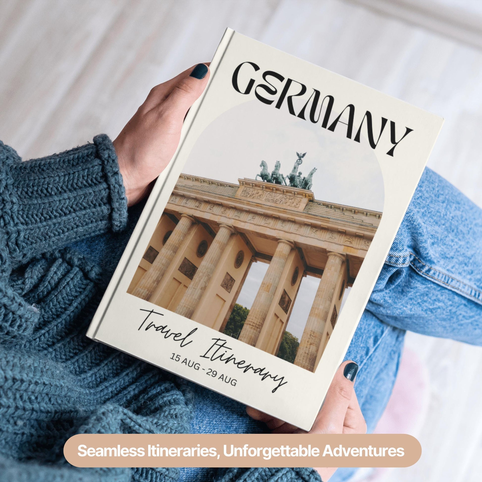 A person wearing a cozy blue sweater and jeans is holding a hardcover travel itinerary book.