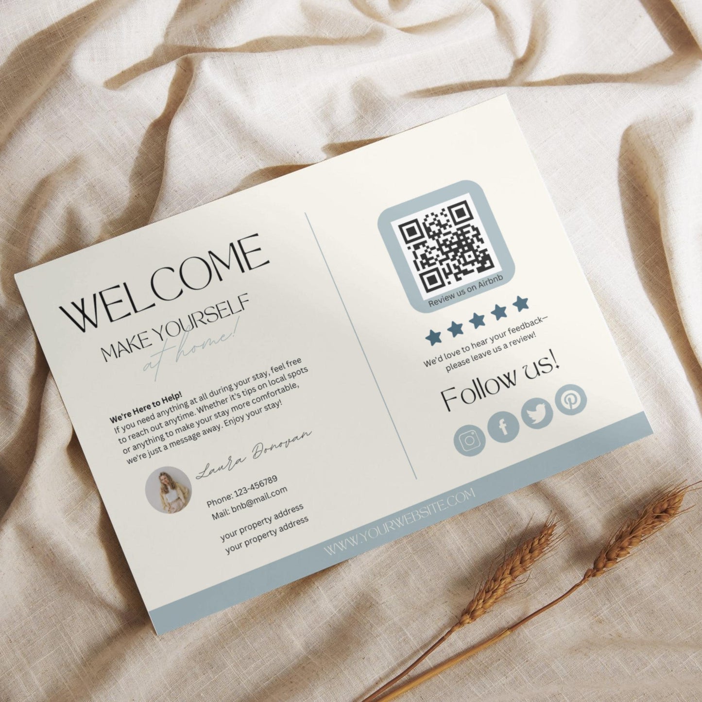 Flat lay of a modern Airbnb welcome card featuring guest information, a QR code for reviews, and social media icons, placed on a light linen fabric with dried wheat stalks.