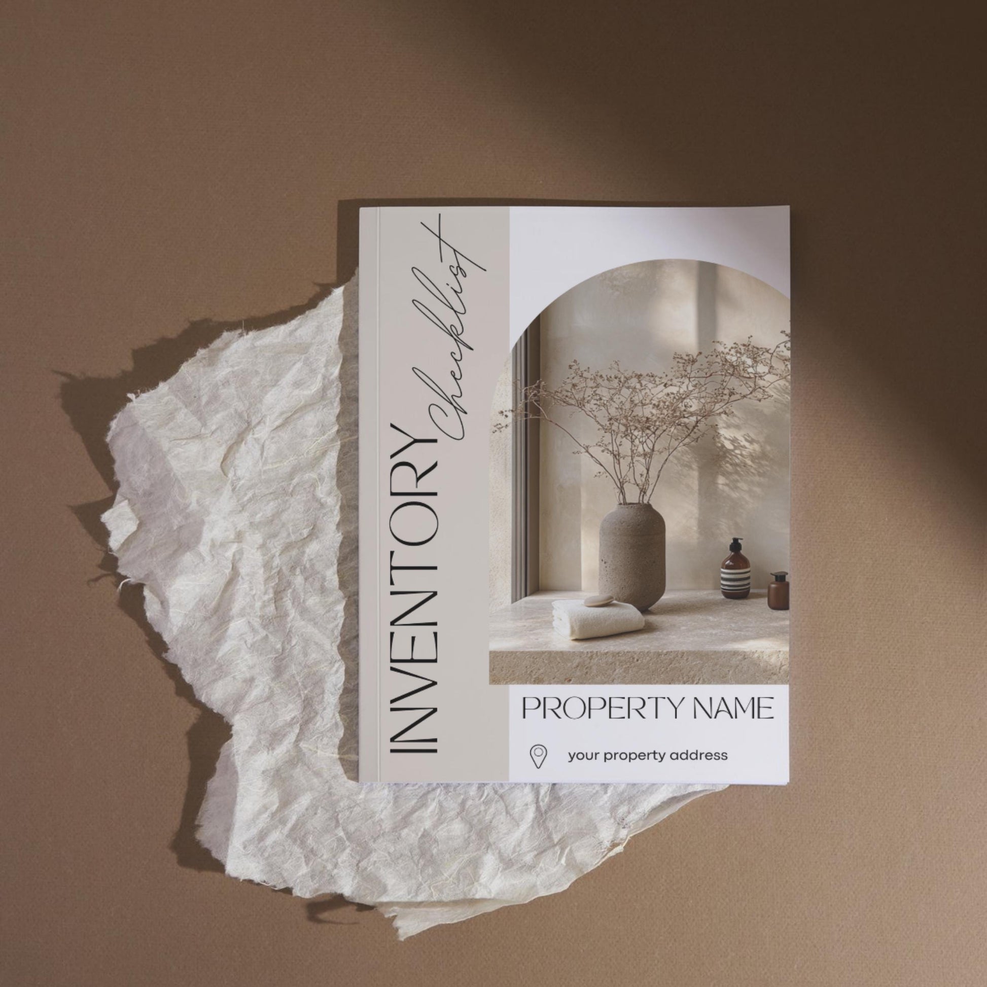 A stylish “Inventory Checklist” booklet is placed on a piece of crumpled white parchment against a warm brown background. The cover features minimalist design elements with soft beige tones and elegant fonts.