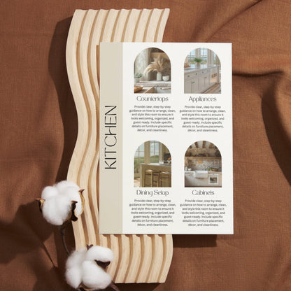 A printed kitchen guide card is placed on a decorative light wood board with a wavy edge, resting on a brown fabric background. The card is titled "KITCHEN" vertically on the left and features four labeled sections with images: Countertops, Appliances, Dining Setup, and Cabinets. 