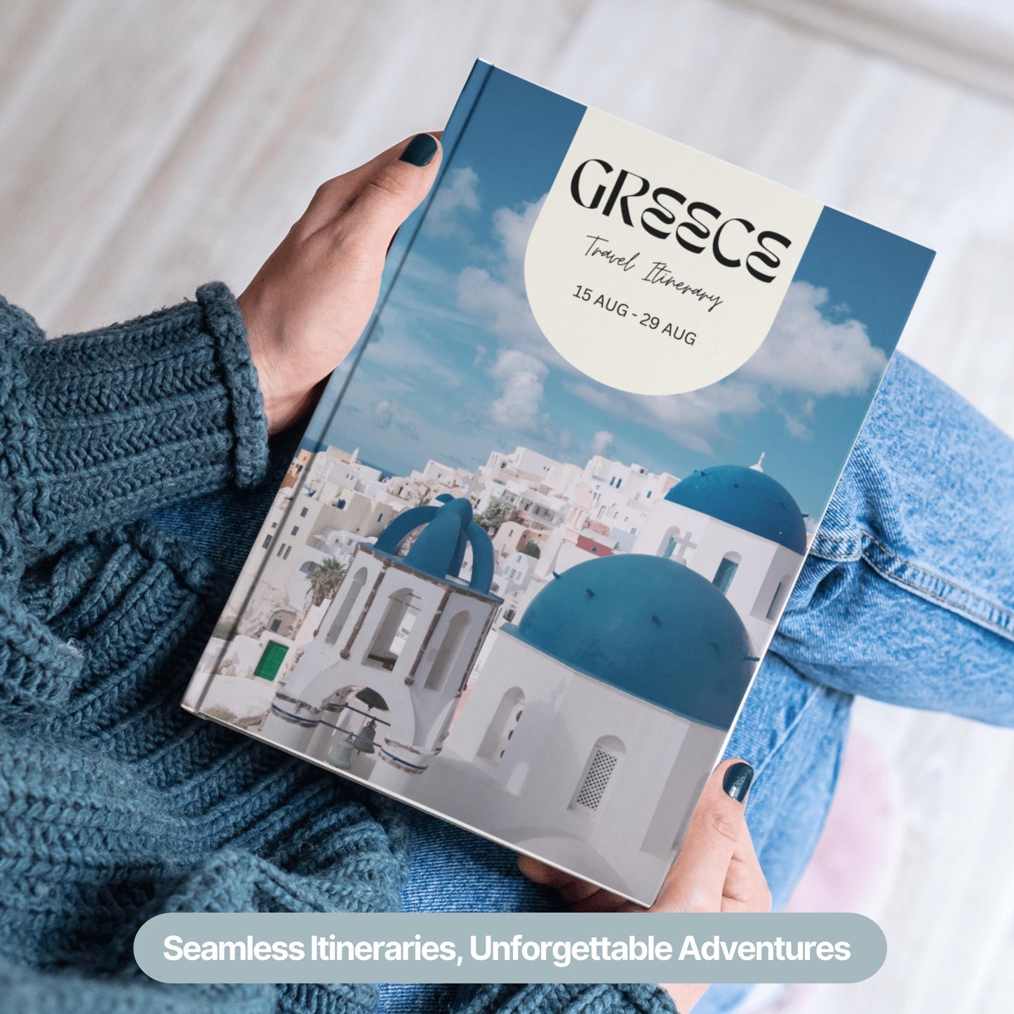 A person wearing a cozy blue sweater and jeans is holding a hardcover travel itinerary book.