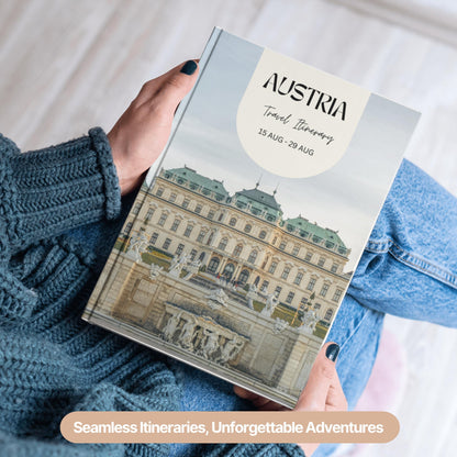 A person wearing a cozy blue sweater and jeans is holding a hardcover travel itinerary book.