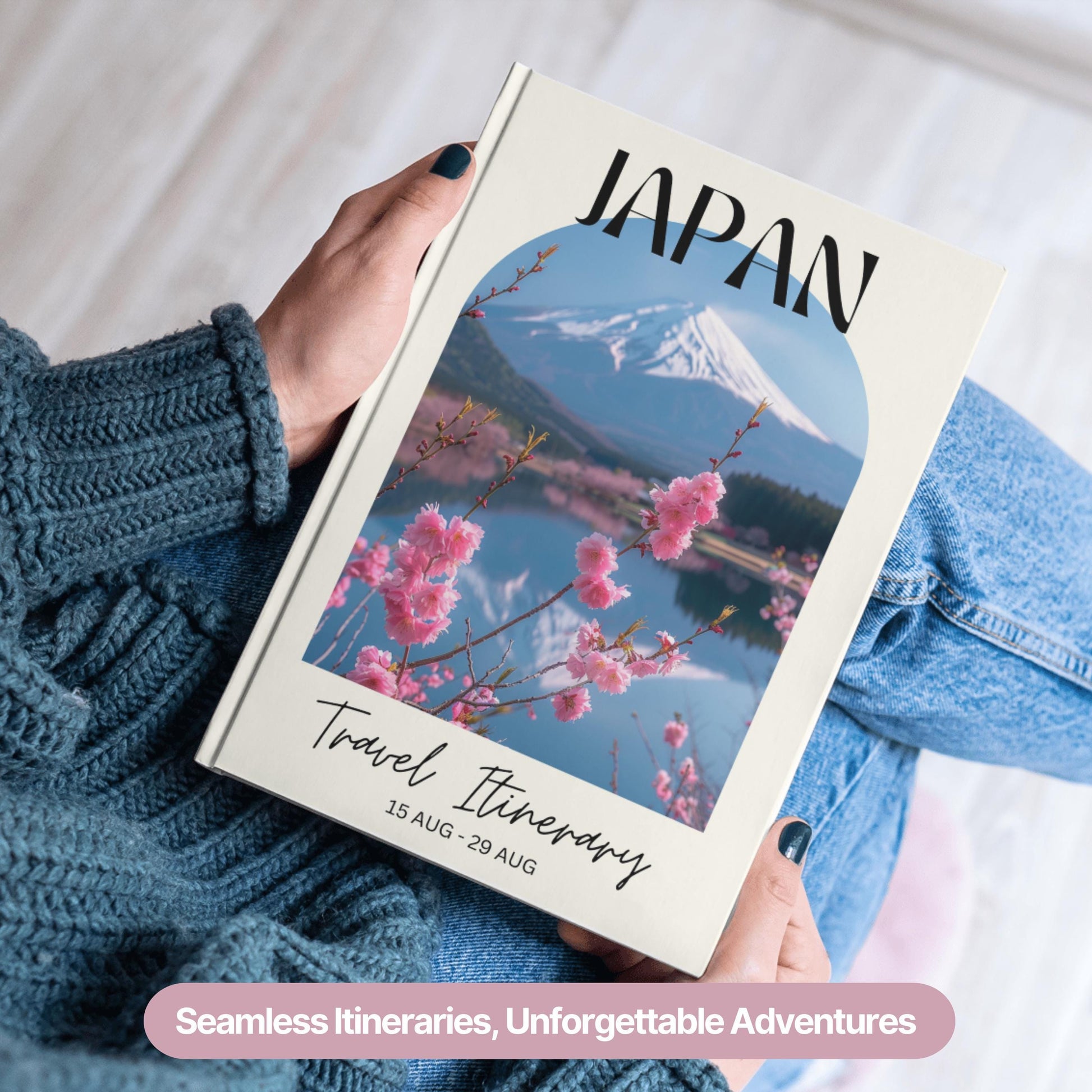 A person wearing a cozy blue sweater and jeans is holding a hardcover travel itinerary book.