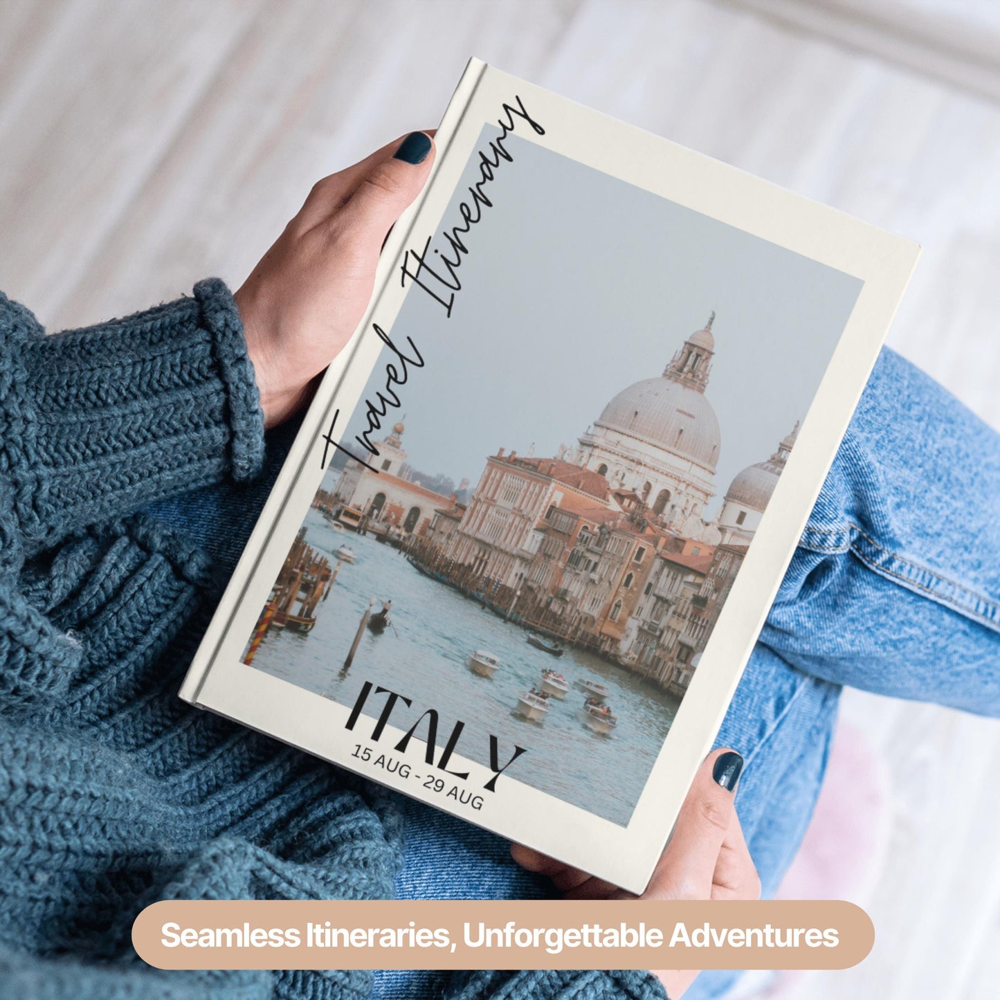 A person wearing a cozy blue sweater and jeans is holding a hardcover travel itinerary book.